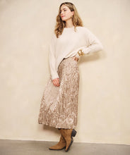 Load image into Gallery viewer, Woman wearing a white sweater and shiny taupe midi skirt and suede brown boots against a white background.
