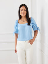 Load image into Gallery viewer, This lovely top features a trend-right square neckline and billowy sleeves detailed with darling ties. The perfect partner to all your denim, or any pair of black or white pants, this feminine style is the ultimate day-to-night piece. Color- Sky blue. Puff sleeve with ties. Square neck. Relaxed fit. Fabric-100% Polyester.
