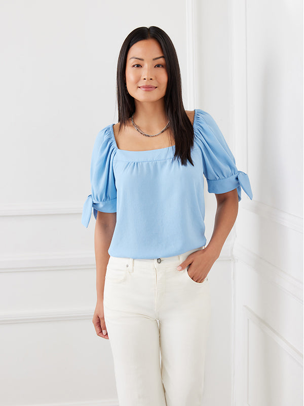 This lovely top features a trend-right square neckline and billowy sleeves detailed with darling ties. The perfect partner to all your denim, or any pair of black or white pants, this feminine style is the ultimate day-to-night piece. Color- Sky blue. Puff sleeve with ties. Square neck. Relaxed fit. Fabric-100% Polyester.