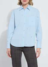 Load image into Gallery viewer, Woman wearing a light blue shirt with embellishments and dark plaid pants against a white background.
