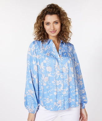 Our Sassa blouse with smock details on the chest and an all-over floral print on a striking blue background is one of a kind! This gorgeous blouse has a wider fit, a collar and button-through closure, while the sleeves have elasticated cuffs.   Colors- Blue, white and gray. Button front. Smocked design on chest. Wider fit. Elasticized cuffs.
