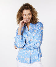 Load image into Gallery viewer, Our Sassa blouse with smock details on the chest and an all-over floral print on a striking blue background is one of a kind! This gorgeous blouse has a wider fit, a collar and button-through closure, while the sleeves have elasticated cuffs.   Colors- Blue, white and gray. Button front. Smocked design on chest. Wider fit. Elasticized cuffs.
