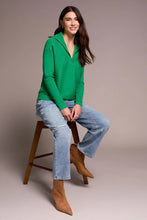 Load image into Gallery viewer, Woman wearing a green sweater, blue jeans and brown boots sitting on a bar stool against a neutral background.

