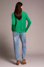 Load image into Gallery viewer, Woman wearing a green sweater, blue jeans and brown boots against a plain background.
