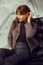 Load image into Gallery viewer, Woman sitting on a black leather couch wearing a sequined jacket, brown top and black leather pants against a gray textured wall.
