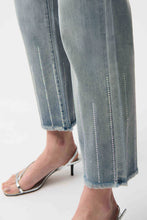 Load image into Gallery viewer, Close-up of light blue jeans with decorative sequin stitching and silver heels on a white background.

