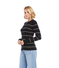 Load image into Gallery viewer, Woman wearing a black sweater with white stripes and light blue jeans against a white wall.
