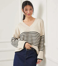 Load image into Gallery viewer, Woman wearing an ecru sweater with black stripes and denim skirt with belt against a white wall.
