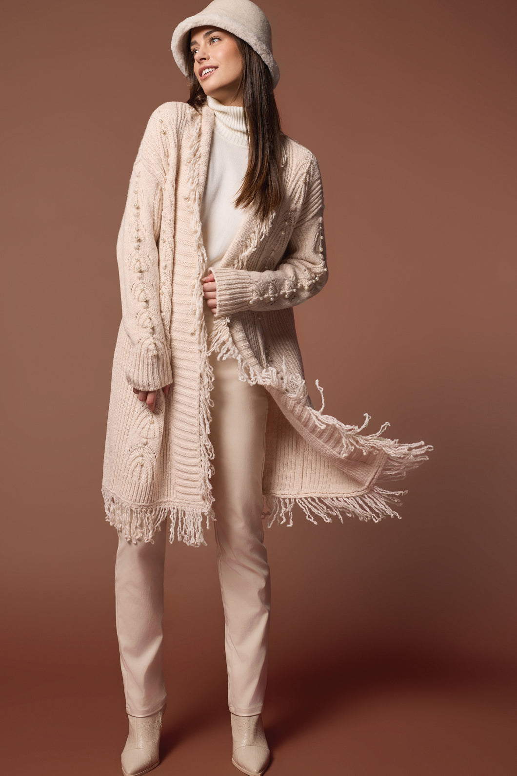 Envelop yourself in elegance with the Senara Sweater Cardigan. This cozy knitted cardigan boasts distinctive descending pearl embellishments along the sleeves and a frilled collar, making it an ideal addition to elevate any outfit.