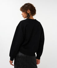 Load image into Gallery viewer, Woman wearing a black sweater, large hoop black sparkle earrings and black sequin skirt against a white background.
