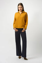 Load image into Gallery viewer, Woman wearing a mustard yellow long-sleeve top, navy pants and heels against a white background.
