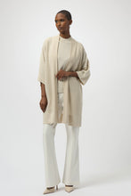 Load image into Gallery viewer, Woman wearing a light warm beige  sparkling three quarter sleeve long knit cover up, white pants and beige heels against a white background. 
