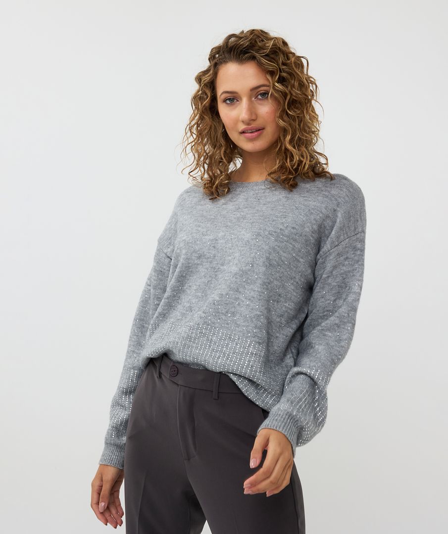 This chic sweater boasts a stylish grey color and is adorned with dazzling rhinestones on the bottom and sleeves, making it a standout piece. Its oversized fit pairs effortlessly with faux leather pants for an edgy, yet sophisticated look, or can be paired seamlessly with denim for a more polished casual style.