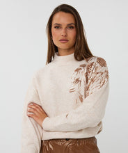 Load image into Gallery viewer, Woman wearing a cream sweater with rose gold floral sequin details and brown leather pants against a plain background.
