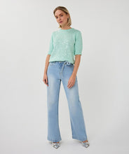 Load image into Gallery viewer, Woman wearing a light mint green short sleeve sequin sweater, blue jeans and silver heels on a white background.
