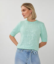 Load image into Gallery viewer, Woman wearing a light mint green short sleeve sequin sweater and blue jeans on a white background.
