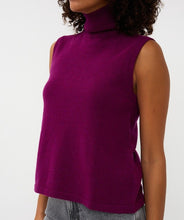 Load image into Gallery viewer, Woman wearing a purple sleeveless turtleneck sweater top and grey jeans against a white background.

