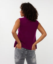 Load image into Gallery viewer, Woman wearing a purple sleeveless turtleneck sweater top and grey jeans against a white background.
