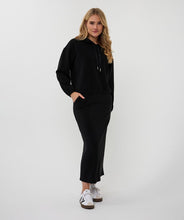 Load image into Gallery viewer, Woman wearing a black outfit with white sneakers against a white background.
