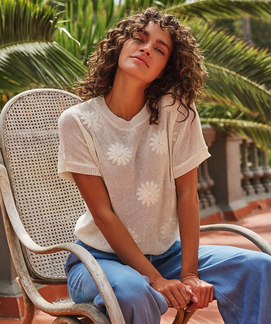 The EsQualo Senia Sweater is a chic, feminine knit featuring delicate floral appliqué and tiny sparkling sequins, a classic round neckline, and short sleeves for effortless style. Crafted from 60% acrylic and 40% polyester, it offers a soft, comfortable fit perfect for layering or wearing solo. this sweater blends elegance and versatility, making it a must-have wardrobe essential.