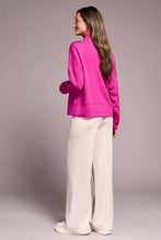 Load image into Gallery viewer, Woman wearing a bright pink funnel neck knit top, white pants and white sneakers against a plain background.
