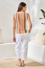 Load image into Gallery viewer, Woman wearing a striped sleeveless top and white pants in a room with a white wall and plant.
