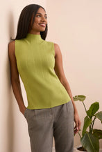 Load image into Gallery viewer, Woman wearing a green sleeveless top and gray pants against a beige wall with a plant.
