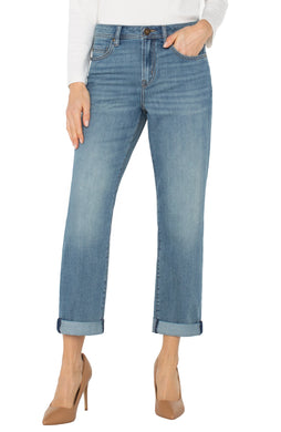 Model wearing white long top, light blue cuffed jeans and beige heels against a white background.