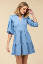 Load image into Gallery viewer, Woman wearing a light blue dress with puffed sleeves against a beige background.
