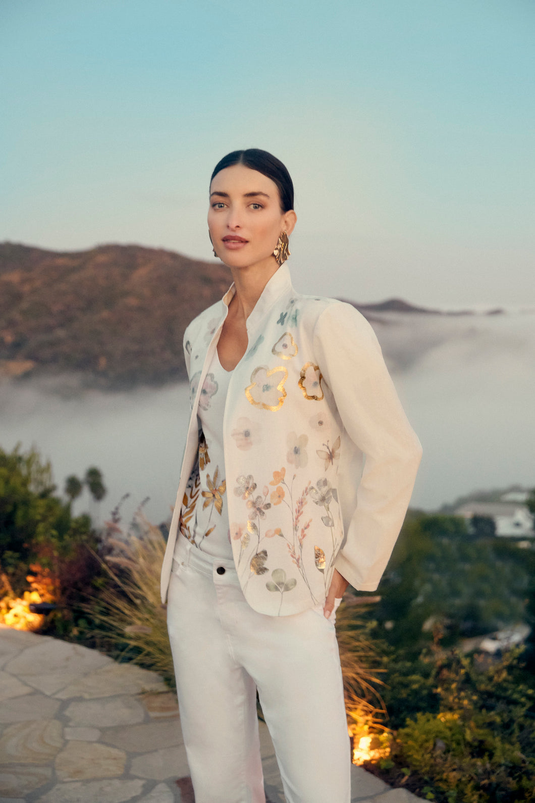 This Frank Lyman open front blazer is the epitome of refined summer layering. Crafted in a soft linen-blend weave, it offers lightweight structure with a flattering drape, perfect for warm-weather sophistication. The open front design and clean lines bring a modern edge, while the crisp white hue and pastel and foil floral pattern keeps it fresh and versatile.