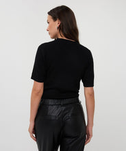 Load image into Gallery viewer, Woman wearing a black short-sleeve  top and black pants against a white background.
