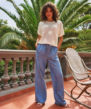 Load image into Gallery viewer, The EsQualo Tudi Trousers Chambray are wide-leg, lightweight pants crafted from 100% Lyocell, offering a soft, breathable feel perfect for warm-weather styling. Designed with an elastic waistband and drawstring, these trousers provide effortless comfort and a relaxed fit. Their versatile chambray fabric pairs beautifully with summer tops, making them a must-have for casual chic looks.
