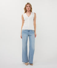 Load image into Gallery viewer, Woman wearing a white sweater vest and blue jeans against a white background.
