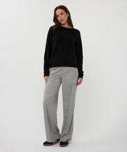 Load image into Gallery viewer, Woman wearing a black sweater, gray pants and black shoes against a white background.
