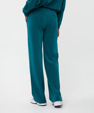 Load image into Gallery viewer, Teal pants and white sneakers worn by a model against a white background.
