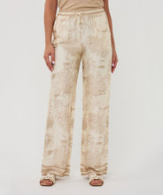 Load image into Gallery viewer, Beige and white safari patterned pants worn by a person on a white background.
