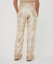 Load image into Gallery viewer, Beige and white safari patterned pants worn by a person on a white background.
