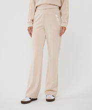 Load image into Gallery viewer, Model wearing beige pants and black and white sneakers against a white background.
