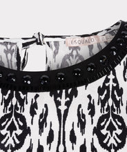 Load image into Gallery viewer, This black and white top features an elegant sleeveless design with a delicate bow at the back and beaded neckline. Perfect for wearing on its own or layering with a jacket or blazer. Experience the timeless chic of an ikat print with this stunning top.
