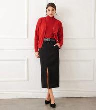 Load image into Gallery viewer, Woman wearing a red cardigan over a coordinating turtleneck, black skirt and black belt and black heels standing against a white wall.
