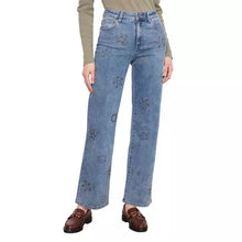Load image into Gallery viewer, A model wearing light blue wide-leg jeans with stud floral embroidery, paired with a beige long-sleeve top and brown loafers, shown against a plain white background.
