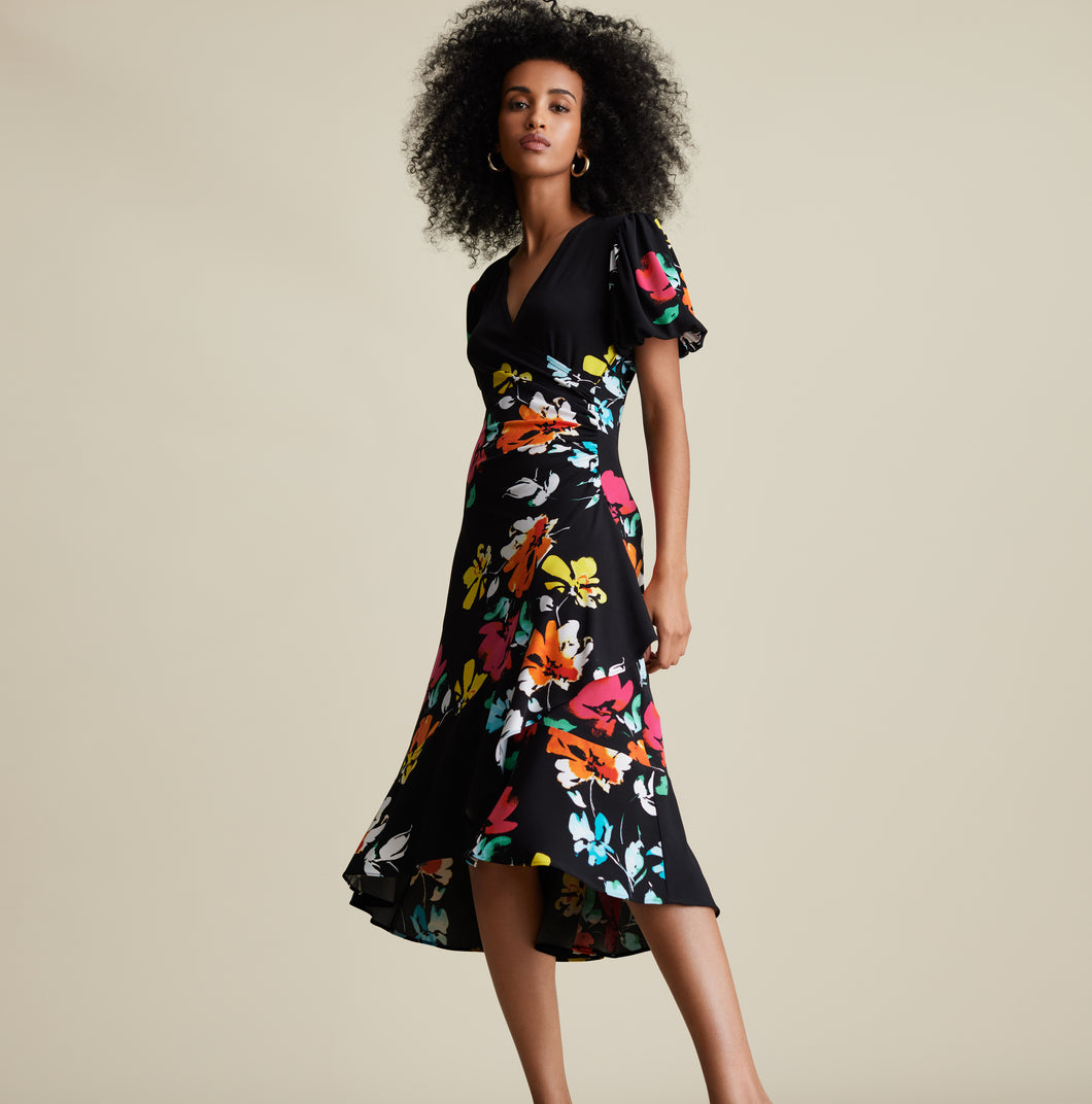Joseph Ribkoff is known for modern and stylish pieces that are beyond gorgeous and this Aria dress fits all of those qualities and more!  A striking floral pattern in various shades of blue, white, orange, yellow and red comes alive on a beautiful black background.  A beautiful V-neck is highlighted with a crossover design leading to rouching at the side.  A billowy sleeve adds to the attractiveness.  For so many dazzling moments in your life, this is the dress of choice!