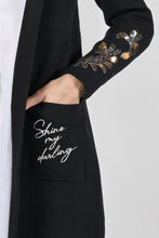 Load image into Gallery viewer, Simply stunning is our Bailey Black Knit and Sequin Cover Up by Frank Lyman.  A beautiful array of shining sequins pop on the black fabric with the words  while the words &quot;Shine My Darling,&quot; written on one pocket, provides a positive affirmation. 
