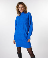 Load image into Gallery viewer, A piercing bright blue color dazzles on this mesmerizing Bettina dress. The classic cable pattern and ribbed cuffs, along with a slightly oversized fit, creates a style that will become your next fashion favorite.  Our Bettina is a beautiful piece to style with leggings and boots or choose to wear alone with boots or heels.  Color- Blue. Pull-over style. Mock-neck. Ribbed cuffs.
