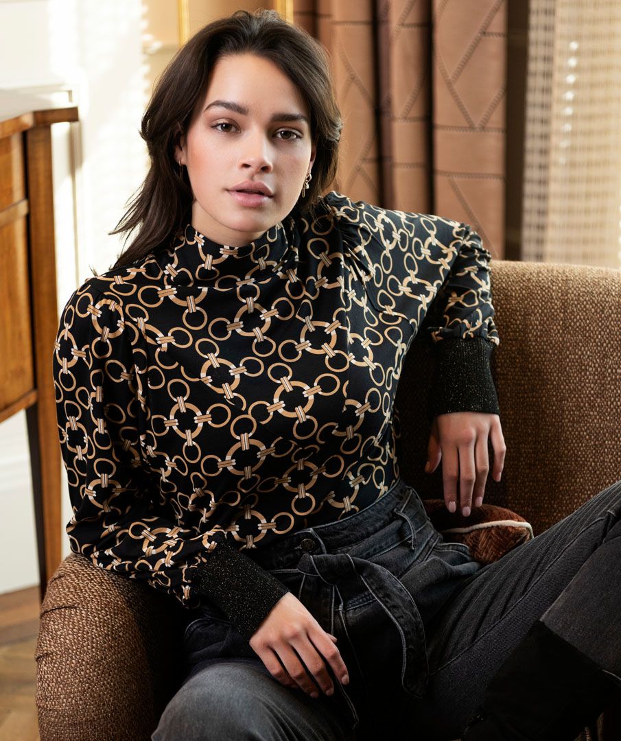 A classic chain print design and ribbed cuffs with a dash of sparkle, creates a style that is effortlessly charming.  A mock neck, pullover style allows our Catharina to pair perfectly with so many of your favorite bottoms, from skirts to denim. Dress up or wear casually; no matter how you style this beauty, you will stand out in a crowd.  Color- Black and gold. Pull over style. Mock neck. Ribbed cuffs with sparkle.