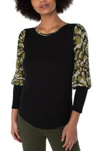 Load image into Gallery viewer, Our Kacie knit top, with floral woven sleeves, transitions effortlessly from season to season. This mixed media top looks beautiful when worn with denim or a pair of your favorite black pants.  Color-Abstract foliage- Black, olive green and white. Woven sleeves. Woven detailing on the back. Foliage trim at the neckline.
