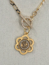 Load image into Gallery viewer, A sparkling statement piece, the Leora necklace is just the right amount of bling to add extra beauty to your outfit.  A vintage Louis Vuitton with its iconic LV symbol delicately sits in a gold floral setting, while the Figaro chain in gold shines brightly in the light.  The toggle closure adds extra brilliance to this fabulous necklace.
