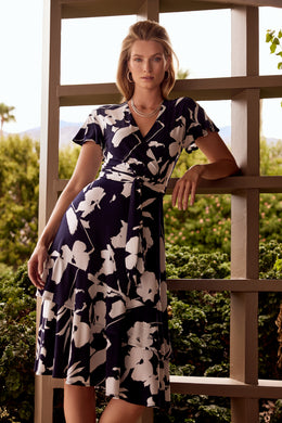 An elegant dress, our Melinda fit and flare dress is a flattering design in a brilliant midnight blue and vanilla color.  Featuring a flattering cross-over front, elastic tie waist double frill hemline and frill cap sleeves this dress has elegant movement and is attractive on all figures.