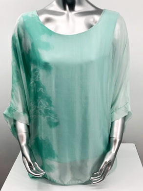 Imagine wearing this incredible top at an outdoor party or out to dinner with friends. A glorious flowy fabrication creates a stunning tunic in a mint tie dye pattern.  Create a classy and fashion forward look with this tunic by pairing it with white bottoms or black slacks.  