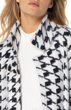 Load image into Gallery viewer, A beautiful combination of a cardigan and a coat creates a coatigan that is warm enough to wear during those cold nights but comfortable enough to wear indoors. Soft and fuzzy, you will wrap yourself in comfort each time you put on this fabulous coatigan. Featuring a beautiful black and white houndstooth pattern, this coatigan pairs well with denim, trousers or leggings!   Color- Black and white. Houndstooth pattern. Open front. Patch pockets.
